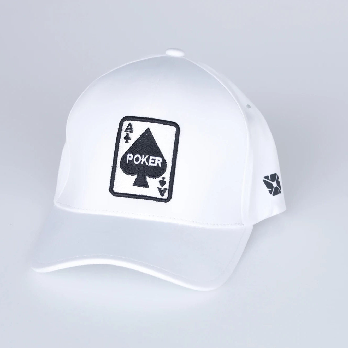 White cap with a black poker-themed logo on a light gray background
