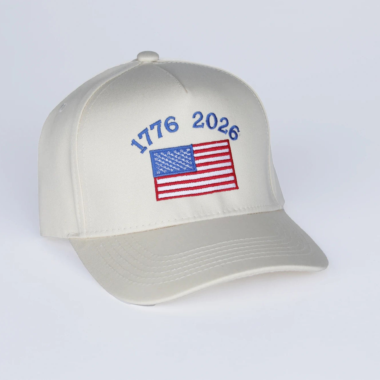 Beige cap with American flag and '1776 2026' text on a white background