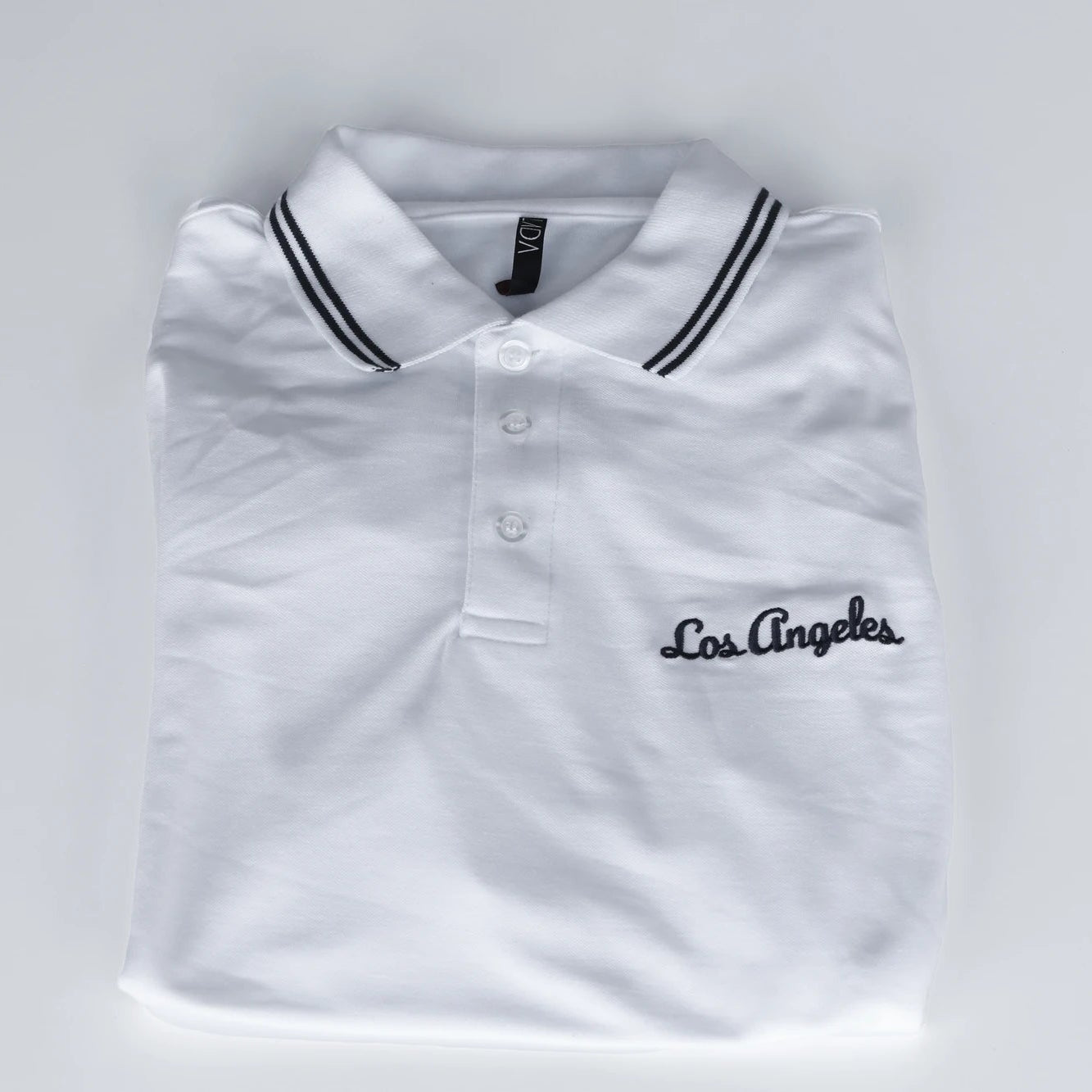 White polo shirt with 'Los Angeles' embroidery on a light gray background
